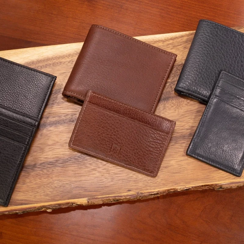 Brown and black leather wallets and card cases on a wooden board